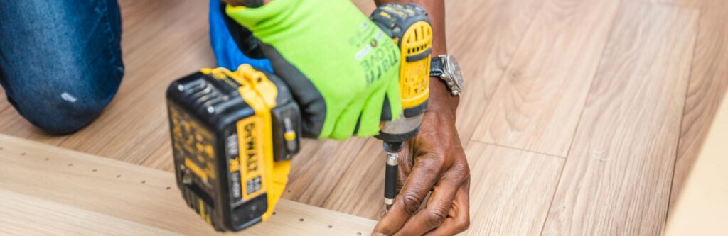 pexels photo 1249610 1249610 Close-up of handyman drilling wood indoors with green gloves and cordless drill.